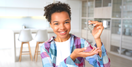 A smiling young female holding a set of housekeys