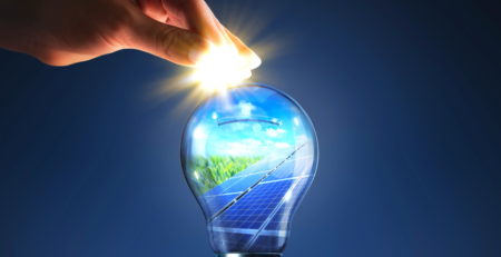 Hand dropping a coin in a lightbulb reflecting solar panels