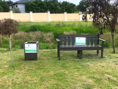 A bark bench and rubbish bin in a park