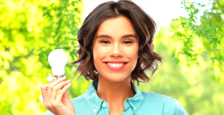 A smiling woman holding an energy efficient light bulb