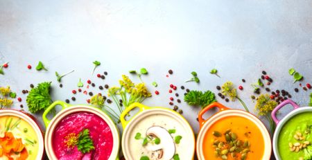 Five bowls of different colourful soups