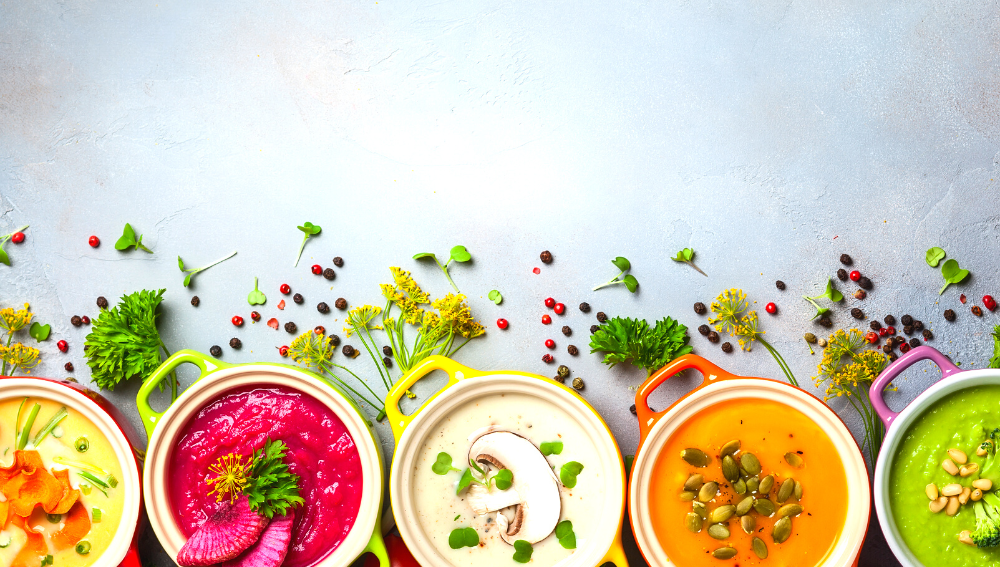 Five bowls of different colourful soups