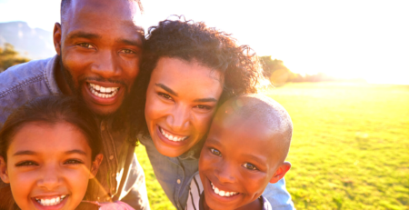 A smiling family in front of a green lawn