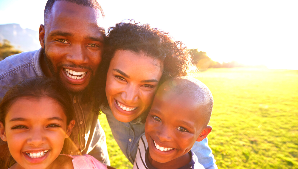 A smiling family in front of a green lawn