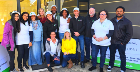 A group foto of the smiling group of STS volunteers in front of the entrance to the Alberton Old Age Home