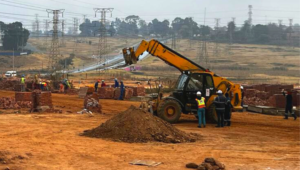Photo of a crane and construction workers on a site.