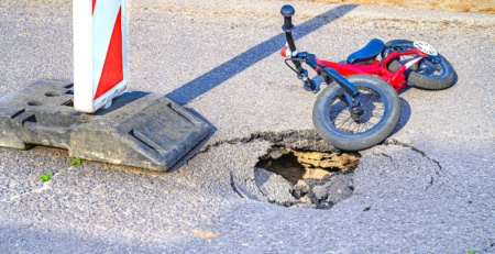 A push bike lying next to a pothole in the road