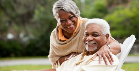 A smiling senior African couple outside