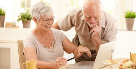 A smiling senior couple looking at a laptop.