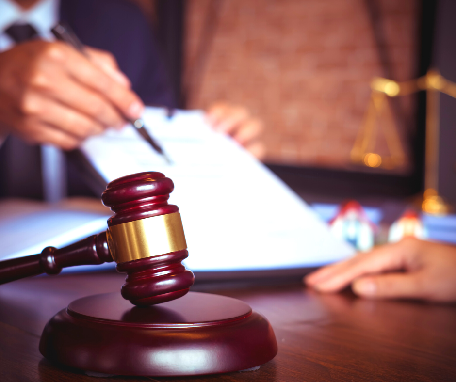 Legal gavel with a person with a pen in hand pointing to a document