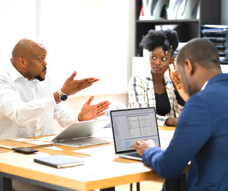 Three people in a meeting with one man looking angry