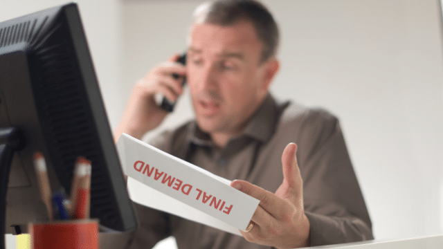 man on the pphone with a final demand letter in his hand
